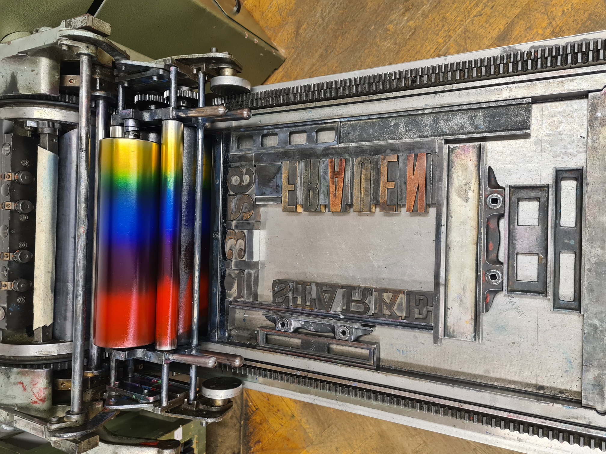Sicht auf den Drucktisch einer Andruckpresse mit einem vorbereiteten Rahmen aus Holzbuchstaben.